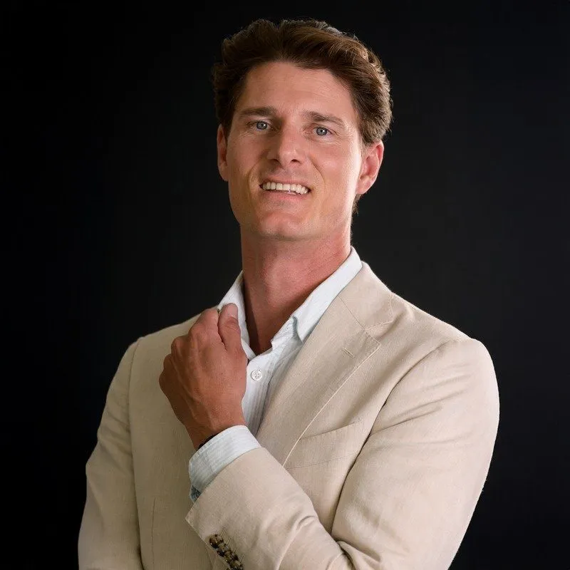 Portrait of Cyrus Truijens in a beige blazer against a black background